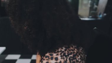 Afro-Amerikan genç bayan şık giyinmiş ve güneş gözlüğü takıyor.