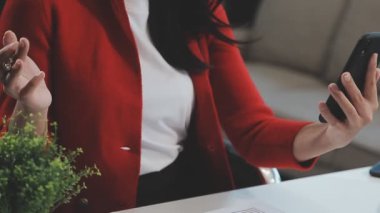 İş kadını cep telefonu kullanıyor ve not defterine notlar yazıyor.