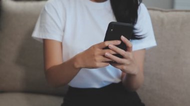 Oturma odasında akıllı telefon kullanan bir kadın.