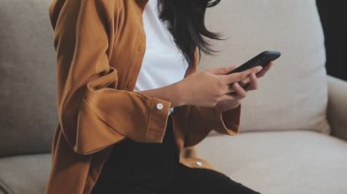 Kanepede akıllı telefon kullanan Asyalı kadınlar.