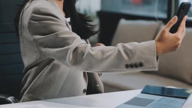 Modern ofisteki listeyi kontrol etmek için cep telefonu kullanan iş kadını