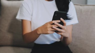 Oturma odasında akıllı telefon kullanan kadın..