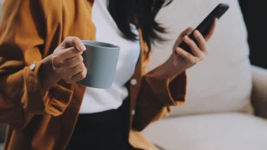 Kafede otururken akıllı telefon kullanan Asyalı kadın.