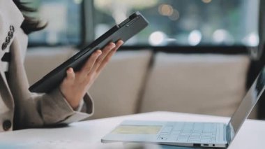 Kadın kafede otururken dijital tablet kullanıyor.