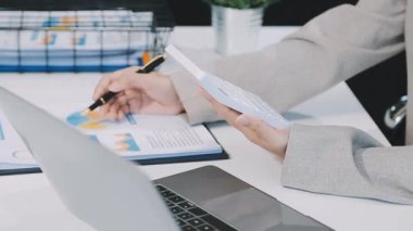 İş kadını hesap makinesi tutuyor ve dizüstü bilgisayar kullanıyor.