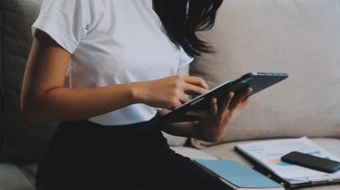 Genç Asyalı kadın oturma odasında tablet kullanıyor, rahatla, ev konseptinden çalış.