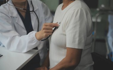 Steteskopla sfenometre kullanan bir doktor hastanede kan basıncını ölçüyor..