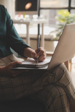 Endişeli genç bir kadının dizüstü bilgisayarla koltukta oturup sorunları düşünmesi dikkatimi dağıtıyor. Düşünceli motivasyonsuz kadın pencereye bakıyor, enerji eksikliği hissediyor, evde uzaktan bağımsız işler yapıyor..