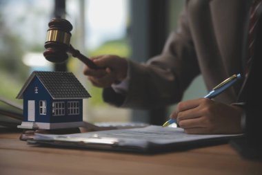 Emlak Hukuku, Ev Sigortası, Emlak Vergisi, Açık Artırma ve Açık Artırma Konsepti. Adliyedeki masasında tokmak adalet çekici olan küçük oyuncak ev modeli..
