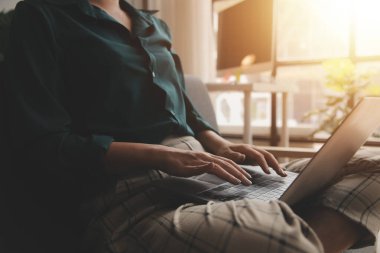 Endişeli genç bir kadının dizüstü bilgisayarla koltukta oturup sorunları düşünmesi dikkatimi dağıtıyor. Düşünceli motivasyonsuz kadın pencereye bakıyor, enerji eksikliği hissediyor, evde uzaktan bağımsız işler yapıyor..