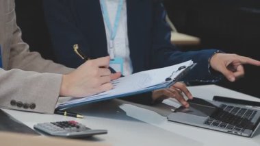 Genç iş kadını ofiste dizüstü bilgisayar ve hesap makinesi kullanıyor..