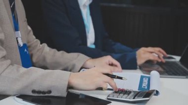 Genç adam modern bir ofiste deftere bir şeyler yazıyor.