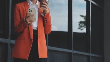 Siyah ceketli bir kadın ve şehirde cep telefonu olan siyah bir elbise.