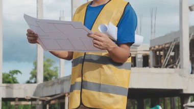 İnşaat mühendisi veya güvenlik yeleği giyen inşaatçı inşaat alanında yeni bir proje üzerinde çalışıyor..