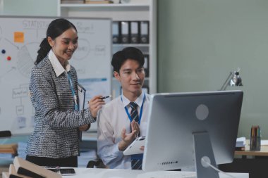 Ofiste dizüstü bilgisayar kullanan neşeli iş adamları. Modern bir çalışma alanında birlikte çalışırken gülümseyen genç girişimciler. Masada birlikte oturan iki genç iş adamı..
