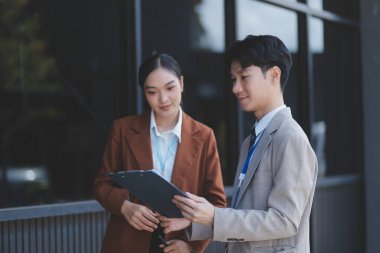 Başarılı genç iş adamları modern iş binası önünde konuşuyor, birlikte çalışıyorlar.