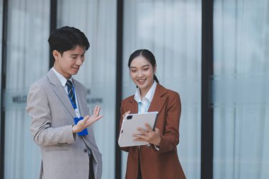 Başarılı genç iş adamları modern iş binası önünde konuşuyor, birlikte çalışıyorlar.