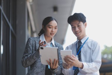 Ofisteki iş arkadaşları ofis binasının dışında yeni projeleri tartışıyor, dijital tablet tutuyorlar. Ofis binalarının önünde duran iki iş arkadaşı iş planını tartışıyor.