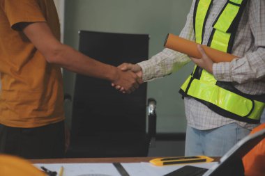 İnşaat alanında el sıkışan mimar adamlar. Çalışan ya da işçi, selamlaşmak, dağıtmak, takım çalışması, işbirliği yapmak için işverenin elini sıkar. Onlar iyi bir takım.