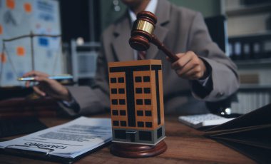 Emlak Hukuku, Ev Sigortası, Emlak Vergisi, Açık Artırma ve Açık Artırma Konsepti. Adliyedeki masasında tokmak adalet çekici olan küçük oyuncak ev modeli..