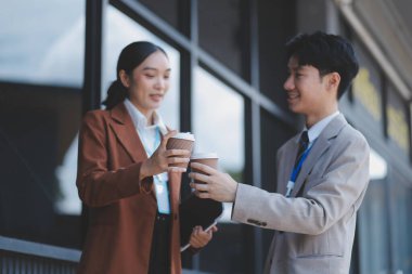 Başarılı genç iş adamları modern iş binası önünde konuşuyor, birlikte çalışıyorlar.