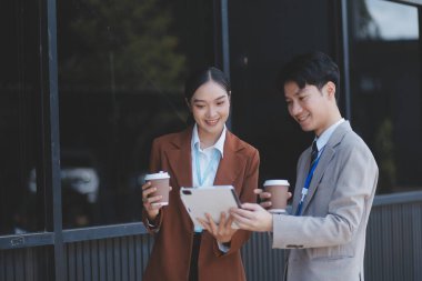 Başarılı genç iş adamları modern iş binası önünde konuşuyor, birlikte çalışıyorlar.