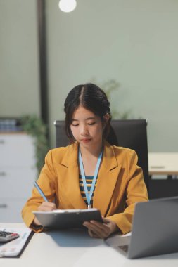 Modern ofis odasında dizüstü bilgisayarla projesinde çalışan çekici genç bir iş kadını..