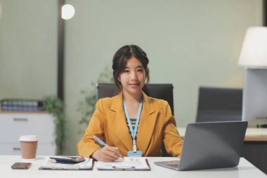 Modern ofis odasında dizüstü bilgisayarla projesinde çalışan çekici genç bir iş kadını..