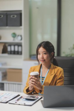 Modern ofis odasında dizüstü bilgisayarla projesinde çalışan çekici genç bir iş kadını..