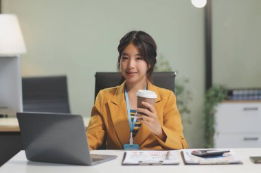 Modern ofis odasında dizüstü bilgisayarla projesinde çalışan çekici genç bir iş kadını..