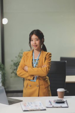 Modern ofis odasında dizüstü bilgisayarla projesinde çalışan çekici genç bir iş kadını..