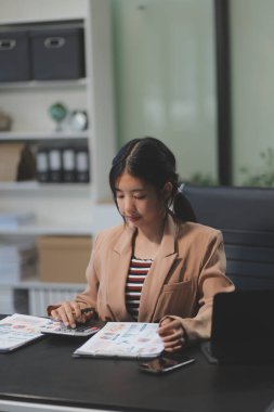Telework konsepti - Asyalı iş kadını video toplantısına katılmak için dizüstü bilgisayar kullanır ve evdeki dijital tabletine notlar yazar