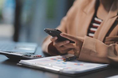 Ofiste çalışırken elinde akıllı telefon tutan Asyalı güzel bir iş kadını..