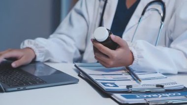 Doktor tablet bilgisayar kullanıyor ve ofiste tıbbi rapor tutuyor..