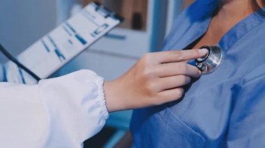 Doktor üniformalı, hastanede steteskopu inceliyor. Ofiste duran doktor ya da hekim. Tıp konsepti