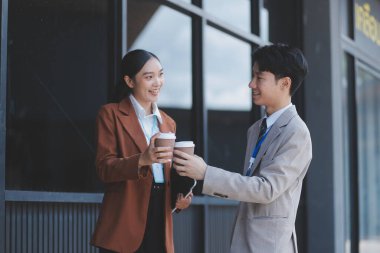Başarılı genç iş adamları modern iş binası önünde konuşuyor, birlikte çalışıyorlar.