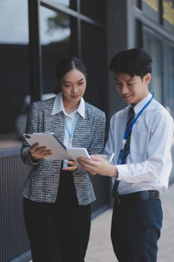 Ofisteki iş arkadaşları ofis binasının dışında yeni projeleri tartışıyor, dijital tablet tutuyorlar. Ofis binalarının önünde duran iki iş arkadaşı iş planını tartışıyor.