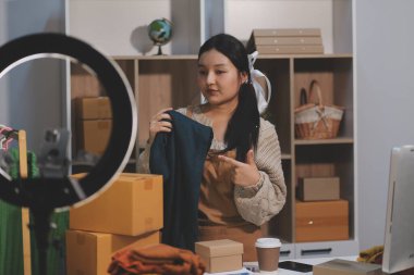 Genç Asyalı kadınlar müşterilerden gelen yeni siparişten sonra mutlu olurlar. Asyalı bir kadının online mağazasının satışındaki başarısının sürpriz ve şok edici yüzü. Çevrimiçi satış. Çevrimiçi Alışveriş