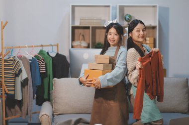 Genç Asyalı kadınlar müşterilerden gelen yeni siparişten sonra mutlu olurlar. Asyalı bir kadının online mağazasının satışındaki başarısının sürpriz ve şok edici yüzü. Çevrimiçi satış. Çevrimiçi Alışveriş