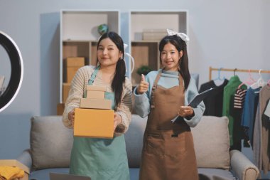 Genç Asyalı kadınlar müşterilerden gelen yeni siparişten sonra mutlu olurlar. Asyalı bir kadının online mağazasının satışındaki başarısının sürpriz ve şok edici yüzü. Çevrimiçi satış. Çevrimiçi Alışveriş