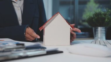 Elinde ev modeli olan bir iş adamı..