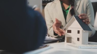 Genç emlakçı ofiste ev modelini sallıyor.