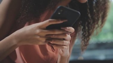 Yakın plan. Sokakta bir sandalyede otururken cep telefonu kullanan genç bir kadın..