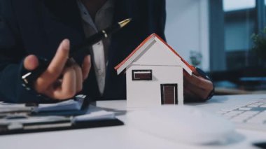 İş adamı ya da emlakçı ev modelinin anahtarlarını elinde tutuyor.