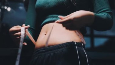 Yağ göbeğini bantla ölçen genç bir kız.