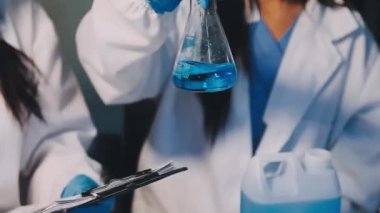 Laboratuvarda sıvı tüpü olan koruyucu üniformalı bilim adamı.