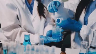 Laboratuvarda kimyasal sıvı ve sıvı içeren matarayı tutan kadın ellerine yakın çekim.