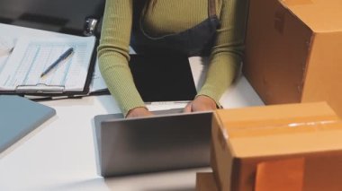 Depoda dizüstü bilgisayar kullanan genç bir kadın.