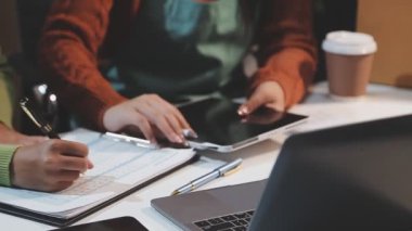 Bilgisayarda çalışan ve ofisteki kağıtlara notlar yazan genç bir kadın..