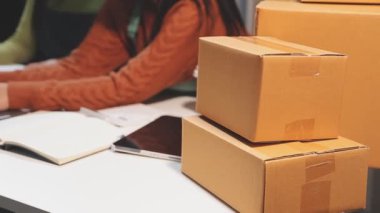 Kadın depoda karton kutu paketliyor.